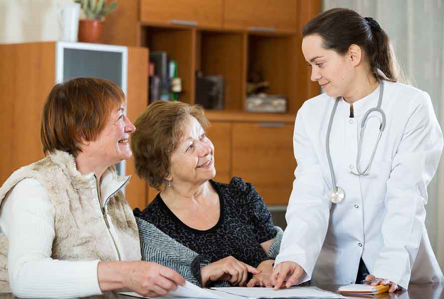 Stock photo of female doctor speaking with two older women